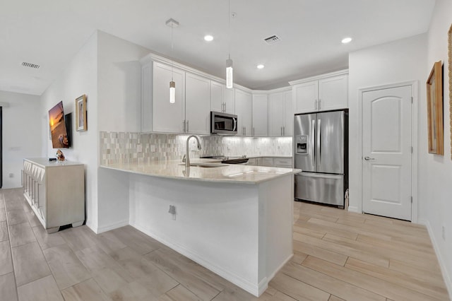 kitchen with white cabinets, sink, stainless steel appliances, and hanging light fixtures