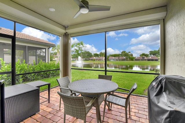 sunroom featuring ceiling fan and a water view