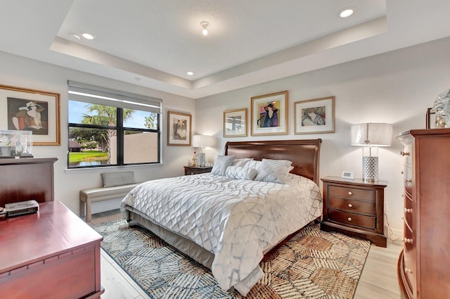 bedroom featuring light hardwood / wood-style flooring and a raised ceiling