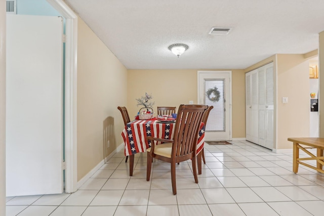 tiled dining room featuring a textured ceiling