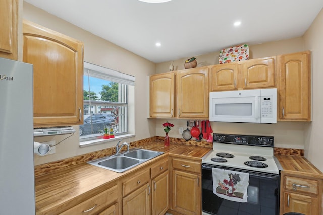 kitchen with butcher block countertops, white appliances, and sink