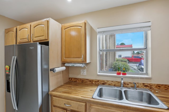 kitchen with butcher block countertops, light brown cabinetry, stainless steel fridge with ice dispenser, and sink