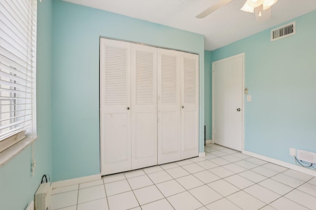 unfurnished bedroom with ceiling fan, light tile patterned floors, and a closet