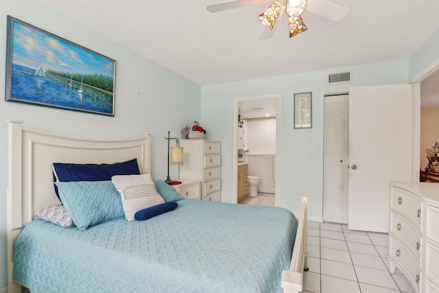 tiled bedroom featuring a textured ceiling, a closet, ensuite bath, and ceiling fan