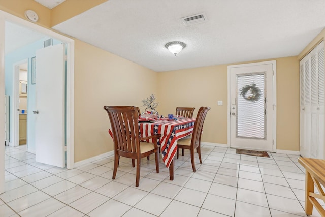 dining area featuring light tile patterned floors and a textured ceiling