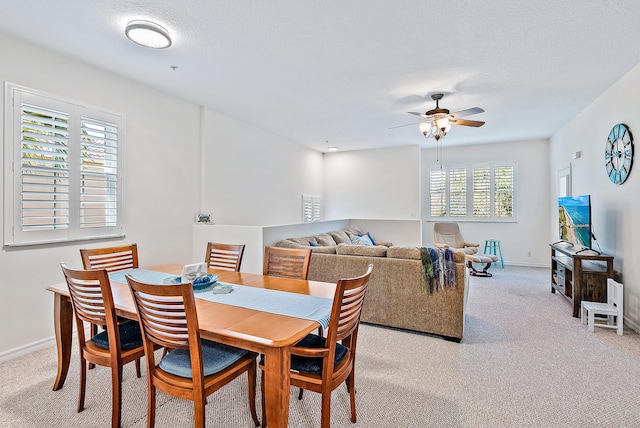 dining room with ceiling fan, light colored carpet, and a textured ceiling