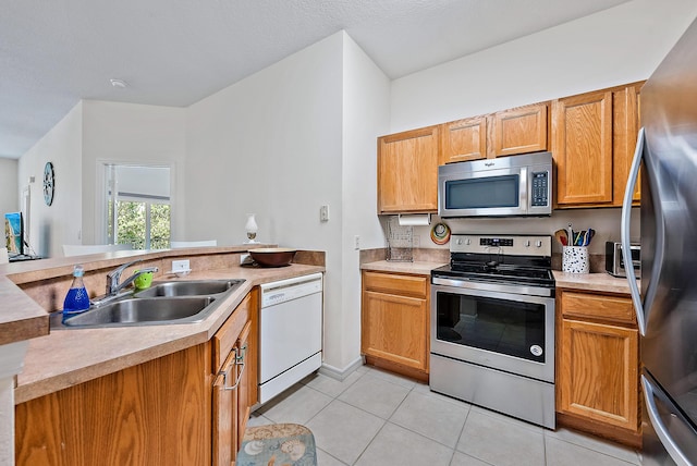 kitchen featuring sink, kitchen peninsula, light tile patterned floors, and appliances with stainless steel finishes