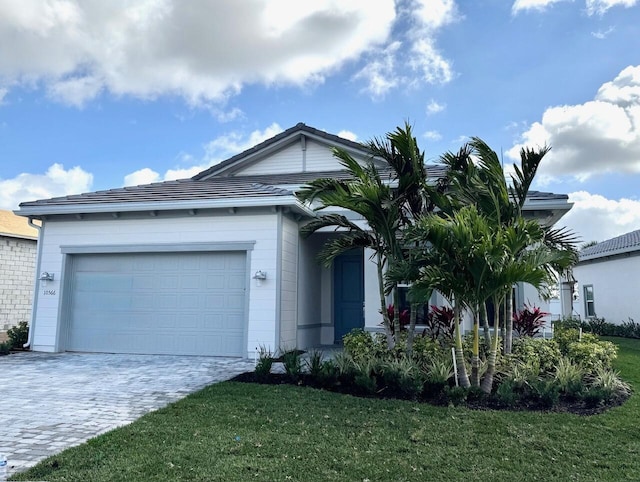 ranch-style home featuring a garage, decorative driveway, and a front yard