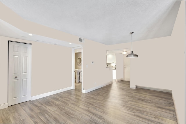 unfurnished living room featuring light wood-type flooring and a textured ceiling