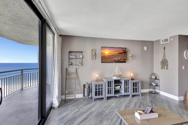 living room with hardwood / wood-style floors, a water view, and a textured ceiling