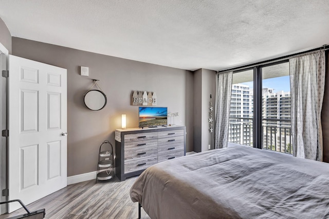 bedroom with a wall of windows, a textured ceiling, access to outside, and multiple windows