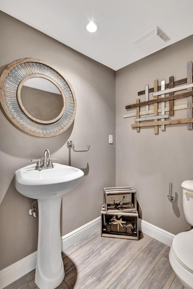 bathroom featuring toilet, wood-type flooring, and sink