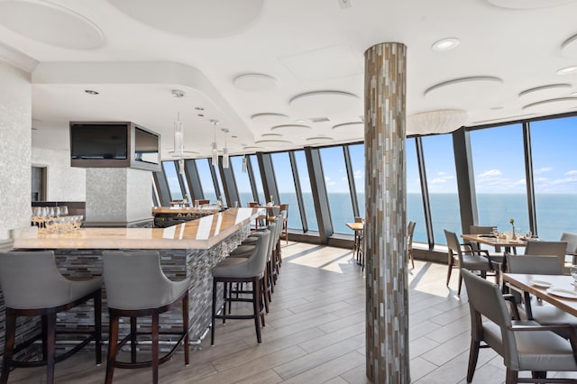 kitchen featuring butcher block counters, expansive windows, a water view, kitchen peninsula, and a breakfast bar area