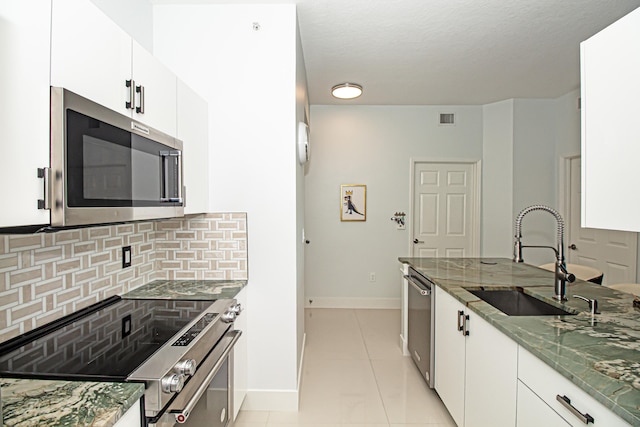 kitchen with white cabinetry, sink, light tile patterned floors, and appliances with stainless steel finishes