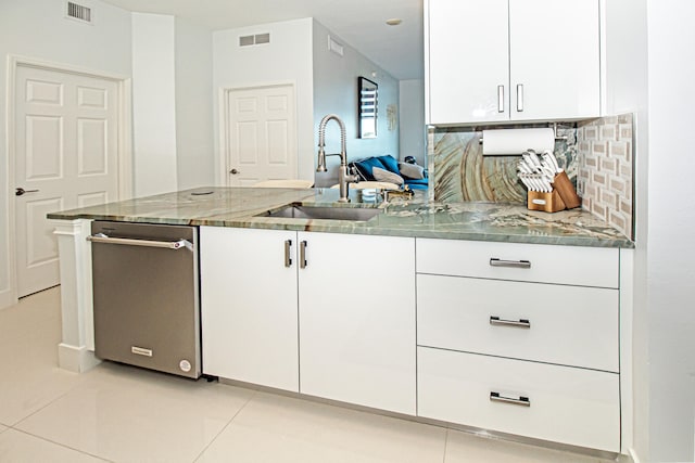 kitchen with light tile patterned floors, white cabinets, stone countertops, and sink