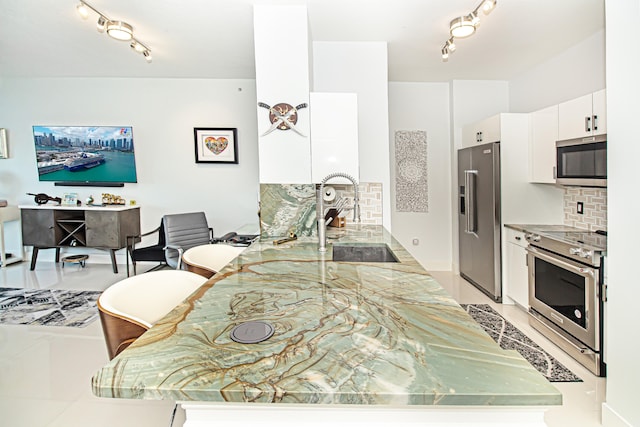 kitchen with white cabinets, kitchen peninsula, sink, and appliances with stainless steel finishes