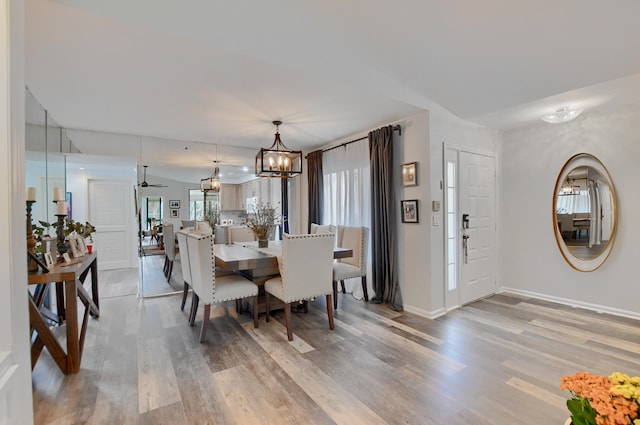 dining room with light hardwood / wood-style floors, ceiling fan with notable chandelier, and a wealth of natural light