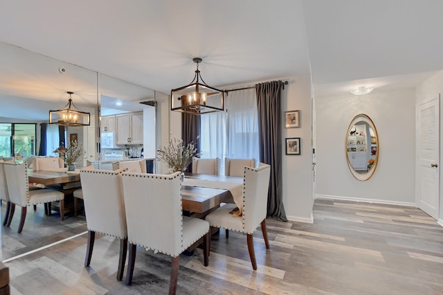 dining room with light hardwood / wood-style flooring and an inviting chandelier