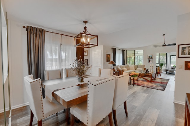 dining space featuring hardwood / wood-style flooring, vaulted ceiling, and ceiling fan with notable chandelier