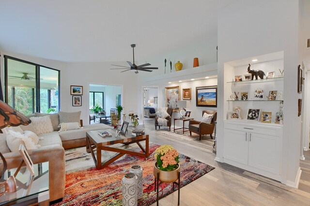 living room with light hardwood / wood-style flooring, high vaulted ceiling, and ceiling fan