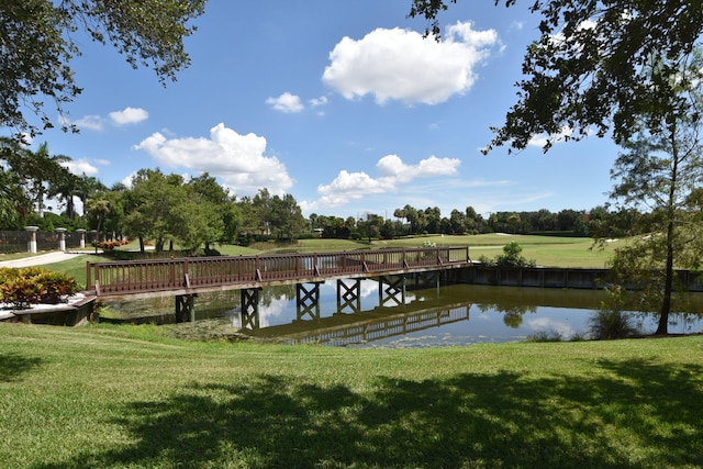 view of dock with a lawn and a water view