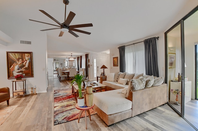 living room featuring light hardwood / wood-style flooring and ceiling fan with notable chandelier