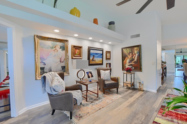 sitting room with light hardwood / wood-style flooring, a towering ceiling, and ceiling fan