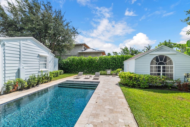 view of swimming pool featuring a lawn, a patio area, and an outbuilding