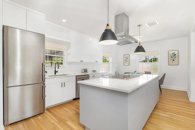 kitchen with white cabinetry, sink, hanging light fixtures, stainless steel appliances, and island exhaust hood