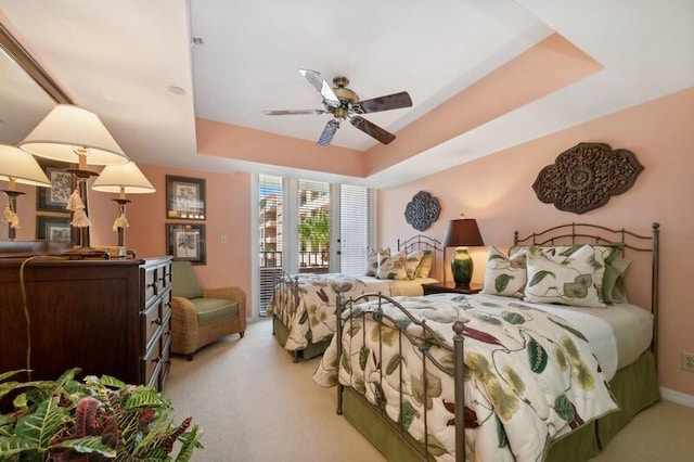 bedroom with access to exterior, ceiling fan, a tray ceiling, and light colored carpet