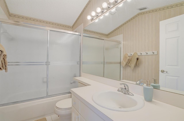 full bathroom featuring bath / shower combo with glass door, vanity, toilet, and a textured ceiling