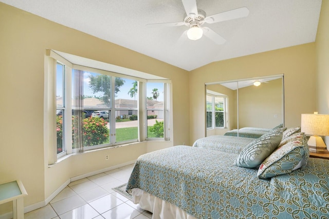 tiled bedroom with ceiling fan, lofted ceiling, and a closet