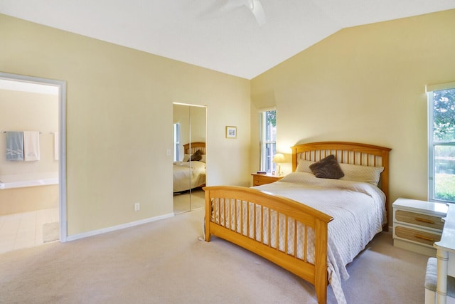 bedroom with ensuite bathroom, lofted ceiling, and light carpet