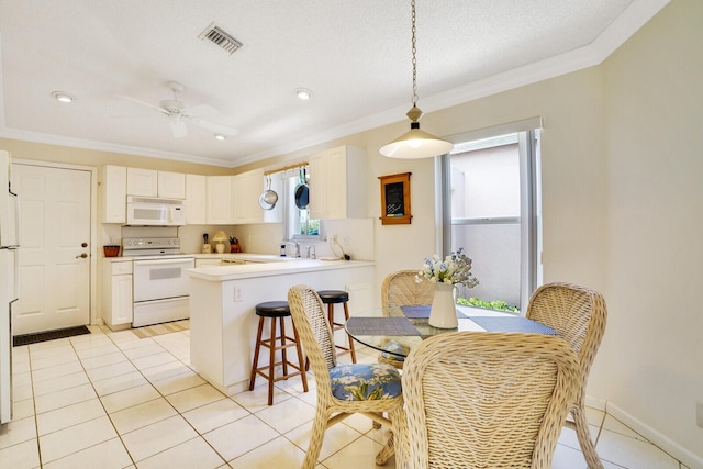 kitchen with crown molding, white cabinets, white appliances, and kitchen peninsula