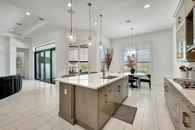 kitchen with appliances with stainless steel finishes, sink, a center island with sink, gray cabinets, and hanging light fixtures