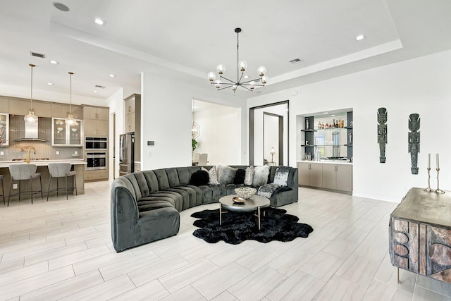 living room featuring a chandelier, sink, and a tray ceiling