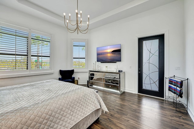 bedroom with a tray ceiling, dark hardwood / wood-style floors, and a notable chandelier