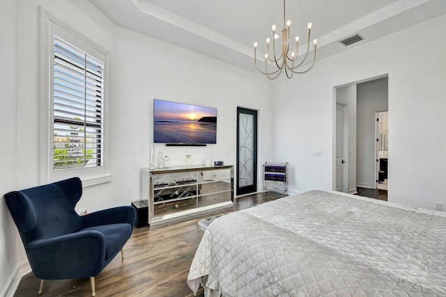 bedroom with a notable chandelier, a raised ceiling, and dark wood-type flooring