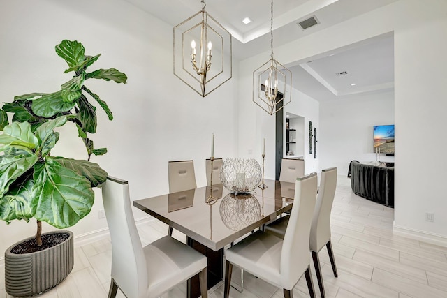 dining room with a raised ceiling and a notable chandelier