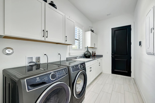 clothes washing area featuring washer and dryer, cabinets, and sink