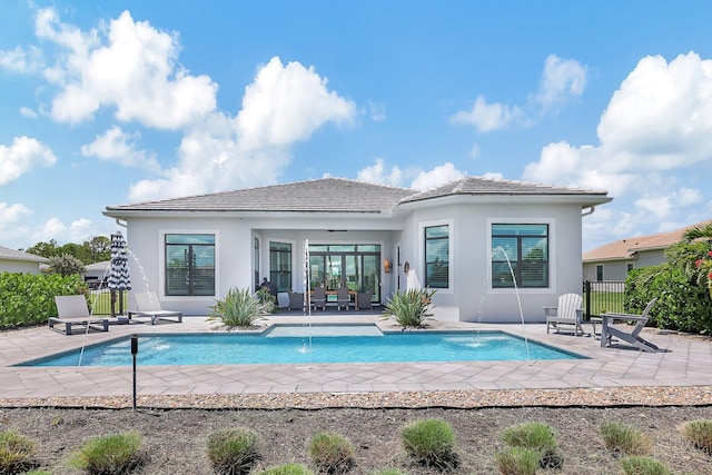 rear view of property featuring pool water feature, a fenced in pool, and a patio