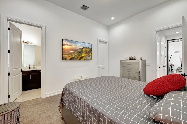 bedroom with ensuite bathroom, sink, and light colored carpet