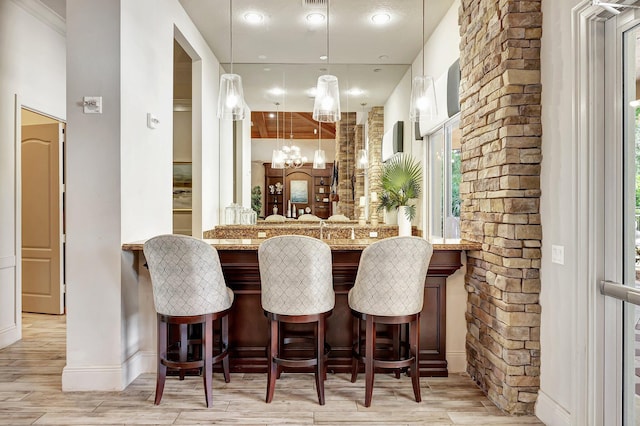 bar featuring a chandelier, light stone counters, and hanging light fixtures