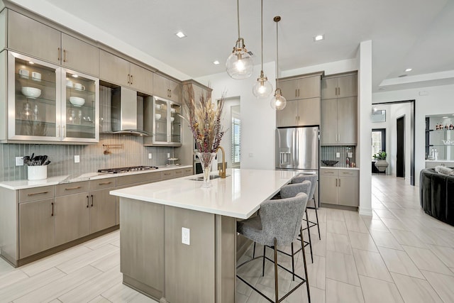 kitchen with a kitchen breakfast bar, wall chimney exhaust hood, stainless steel appliances, a spacious island, and sink