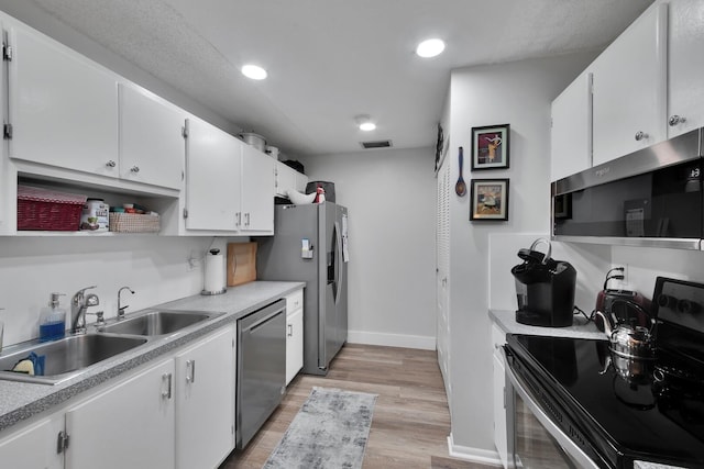 kitchen featuring white cabinets, stainless steel appliances, light hardwood / wood-style flooring, and sink