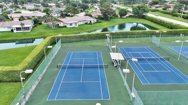 view of tennis court featuring basketball hoop and a water view