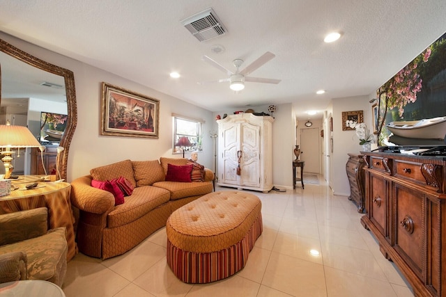 living room featuring ceiling fan, light tile patterned flooring, and a textured ceiling