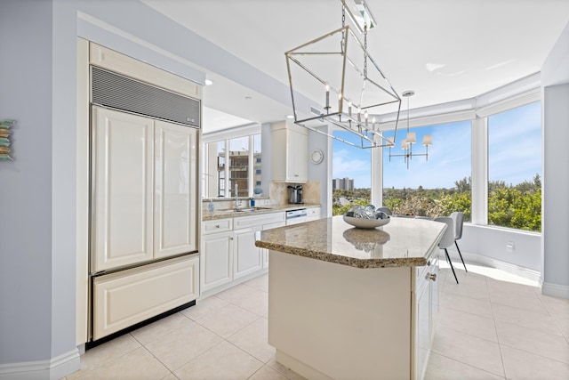 kitchen with white cabinetry, paneled built in refrigerator, pendant lighting, a chandelier, and light tile patterned floors