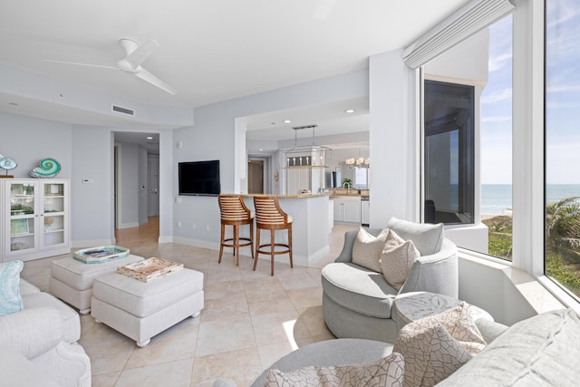 tiled living room with ceiling fan with notable chandelier