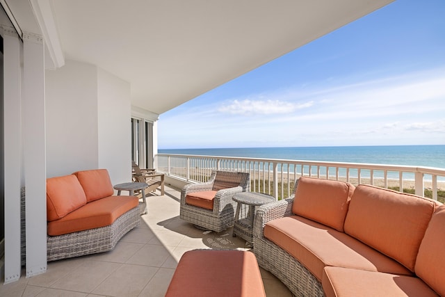 balcony with outdoor lounge area, a water view, and a beach view